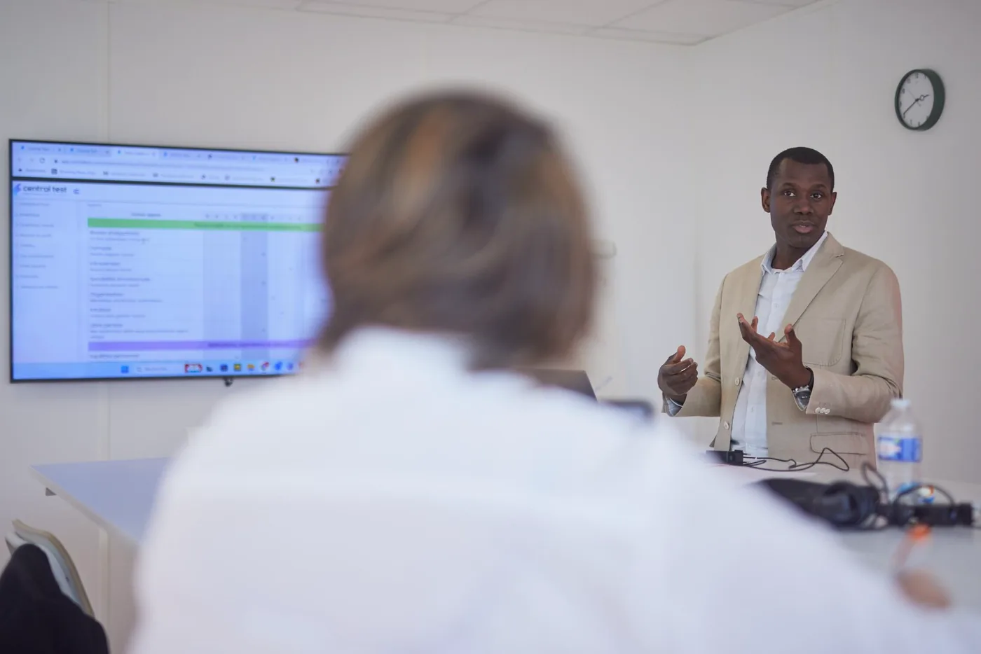 M. Traoré debout devant un grand écran, présentant un document à plusieurs participants lors d'une formation professionnelle